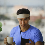 Man wearing a Growband Pro, holding a mug and phone, with a blurred outdoor background
