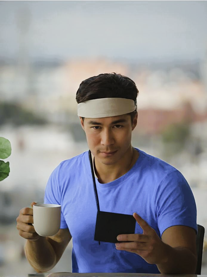 Man wearing a Growband Pro, holding a mug and phone, with a blurred outdoor background